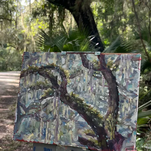 An oil painting of a tree and surrounding landscape, created outdoors in a natural setting.