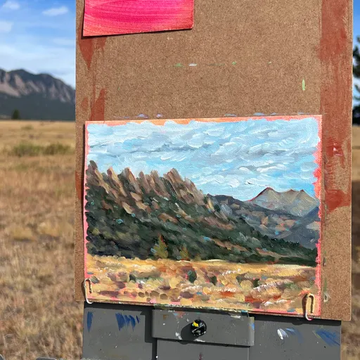 A small oil painting depicting a mountain landscape with a field in the foreground under a blue sky.