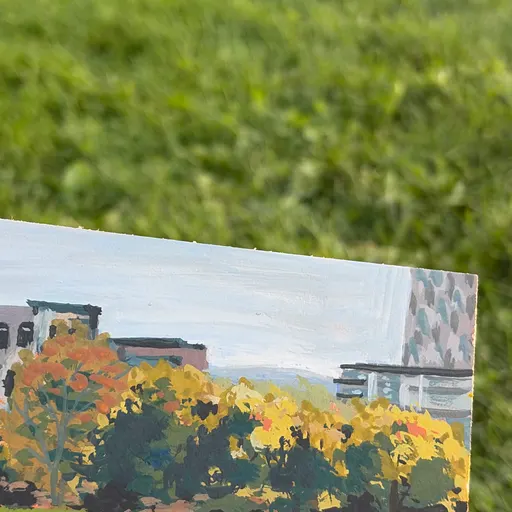 A serene park scene with autumn-colored trees, a few buildings in the background, and two figures sitting on the grass.